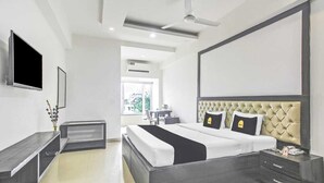 Ein modernes Hotelzimmer mit einem großen Bett, einem Flachbildfernseher, einem Deckenventilator und Blick ins Freie.