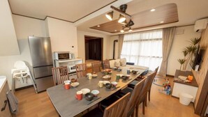 Eine moderne Küche mit Essbereich, Holzkreislern, einem großen Tisch und einem Kühlschrank.
