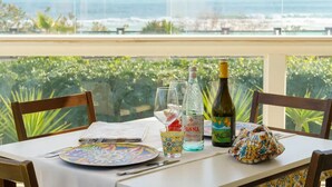 A table set for two with a view of the ocean, a bottle of wine, and a decorative bag. - HOTEL JONIO (Noto)