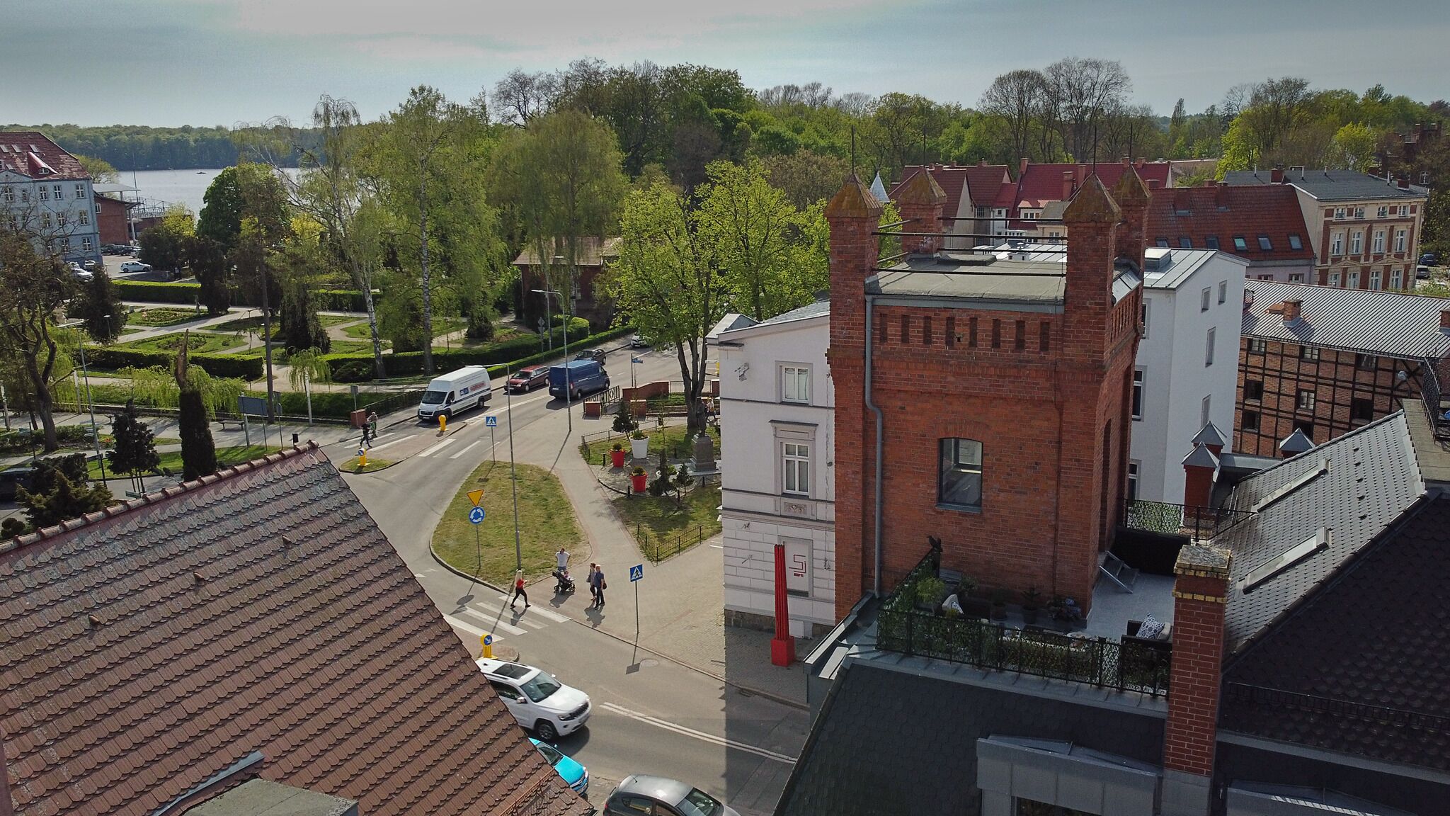 Ein Wohngebiet mit einer Mischung aus moderner und traditioneller Architektur, darunter ein markantes Backsteinhaus mit rotem Dach und ein Gebäude mit flachem Dach.