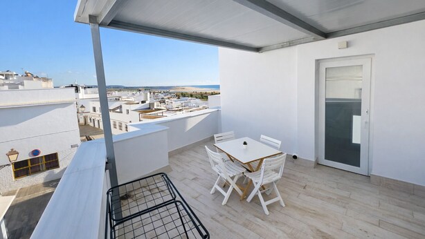 Ein Balkon mit Tisch und Stühlen, einer Tür und Blick auf die Stadt.