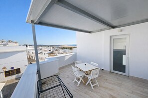 A balcony with a table and chairs, a door, and a view of the cityscape. - Apartamento Puerta Cai III (Conil de la Frontera)