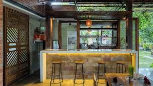 Un espace bar avec un comptoir, des tabourets et une vue sur l’extérieur.