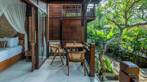 Un balcon en bois avec un lit, deux fauteuils en osier et une petite table.