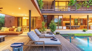 Un espacio exterior moderno con piscina, sillones de descanso y zona de comedor.