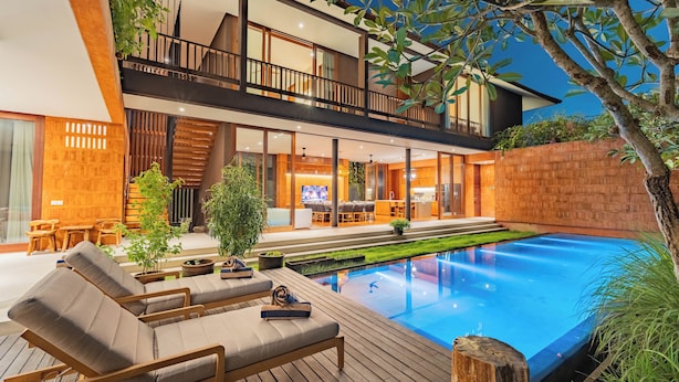 Una casa moderna de dos pisos con piscina, mobiliario exterior y un jardín bien cuidado.