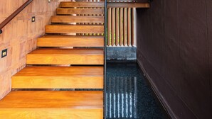 Una escalera con escalones de madera y barandilla de metal, que conduce a un suelo oscuro.