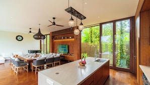 Una cocina moderna con una isla grande, armarios de madera y un comedor con mesa y sillas.