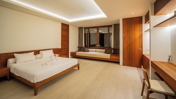 A modern bedroom with a large bed, a built-in bench, a wooden desk, and a mirror. - Rosa Village (Jimbaran)
