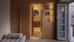 Un baño moderno con muebles de madera, tocador de mármol y cabina de ducha de vidrio.