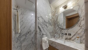 Un baño con paredes de mármol, un mueble de madera, un lavabo y un espejo.