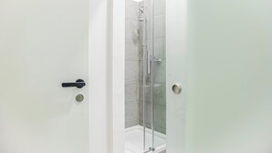 A bathroom with a glass shower enclosure, a white door, and a visible lock. - Stylish 2BR Apt Near AKH Easy Center (Vienna)