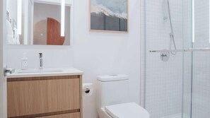 A modern bathroom with a wooden vanity, a toilet, and a glass shower enclosure. - Revelstoke - Gary's Birthday- New condo! (Revelstoke)