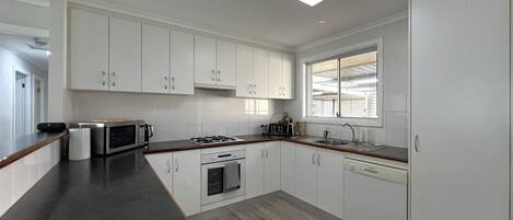 Una cocina moderna con armarios blancos, encimera negra, tragaluz y ventana.