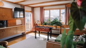 Une pièce chaleureuse avec un baby-foot, des meubles en bois, une télévision et une fenêtre avec des rideaux.