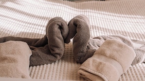 Un lit avec une couvre-lit à carreaux, deux oreillers et une paire de serviettes pliées.