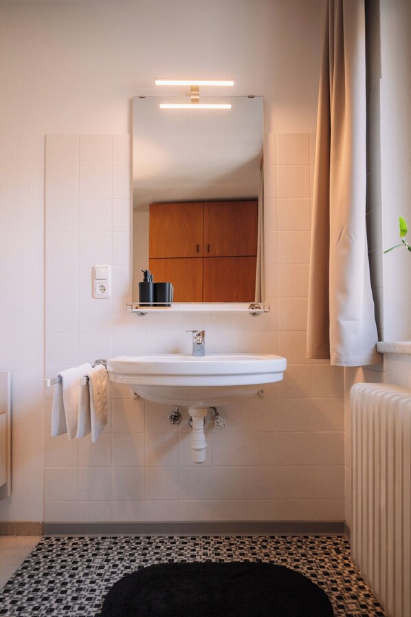 A bathroom with a white sink, a mirror, and a towel rack.