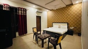 Ein Hotelzimmer mit Bett, Schreibtisch, zwei Stühlen, Kleiderschrank und einer Wand mit Muster.