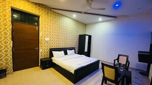 Ein Hotelzimmer mit einem Bett, einem Schreibtisch mit Stuhl, einem Deckenventilator und einem Kleiderschrank.