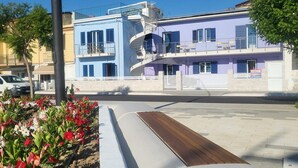 Un edificio moderno con facciata blu e viola, una scala a chiocciola e una panchina in primo piano.