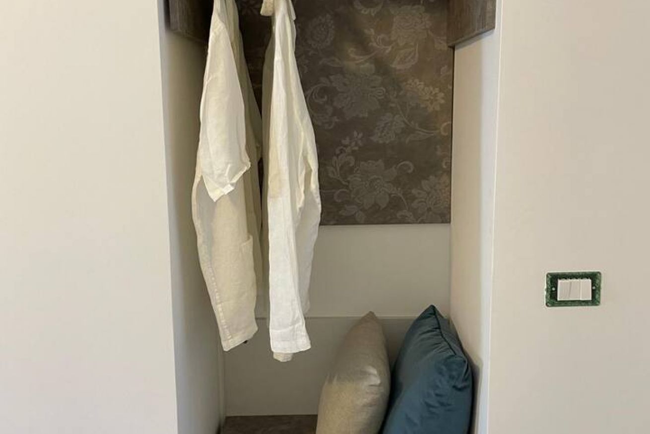 A room with a bed, a pillow, and a wall-mounted light switch.
