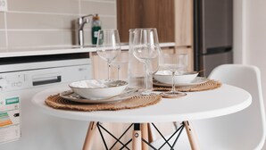 A dining table with white plates, clear glasses, and a placemat in a modern kitchen with a white countertop and wooden cabinets. - Casa De Lior- Luxury Apartment (Sandton)