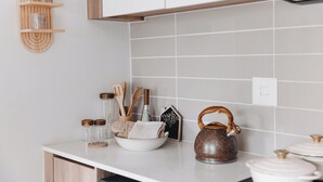 A kitchen with white cabinets, a wooden shelf, a kettle, and various kitchen utensils. - Casa De Lior- Luxury Apartment (Sandton)