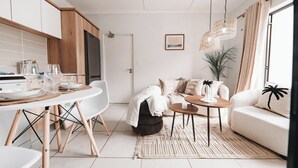 A modern kitchen with white cabinets, a dining table with chairs, a sofa, and a coffee table. - Casa De Lior- Luxury Apartment (Sandton)