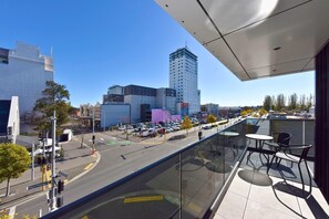 En høj bygning med en glasbalkon med udsigt over en gade.