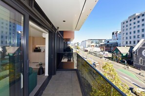 A modern building with a balcony overlooking a street with shops and buildings. - Freshly Styled 1BR Apartment near Te Kaha Stadium (Christchurch)