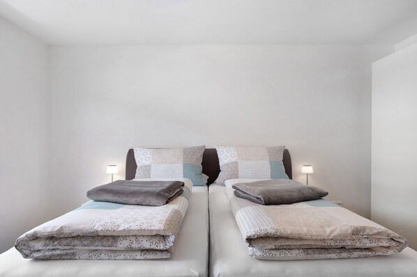 A twin bed with a headboard, two bedside lamps, and a patterned bedspread.