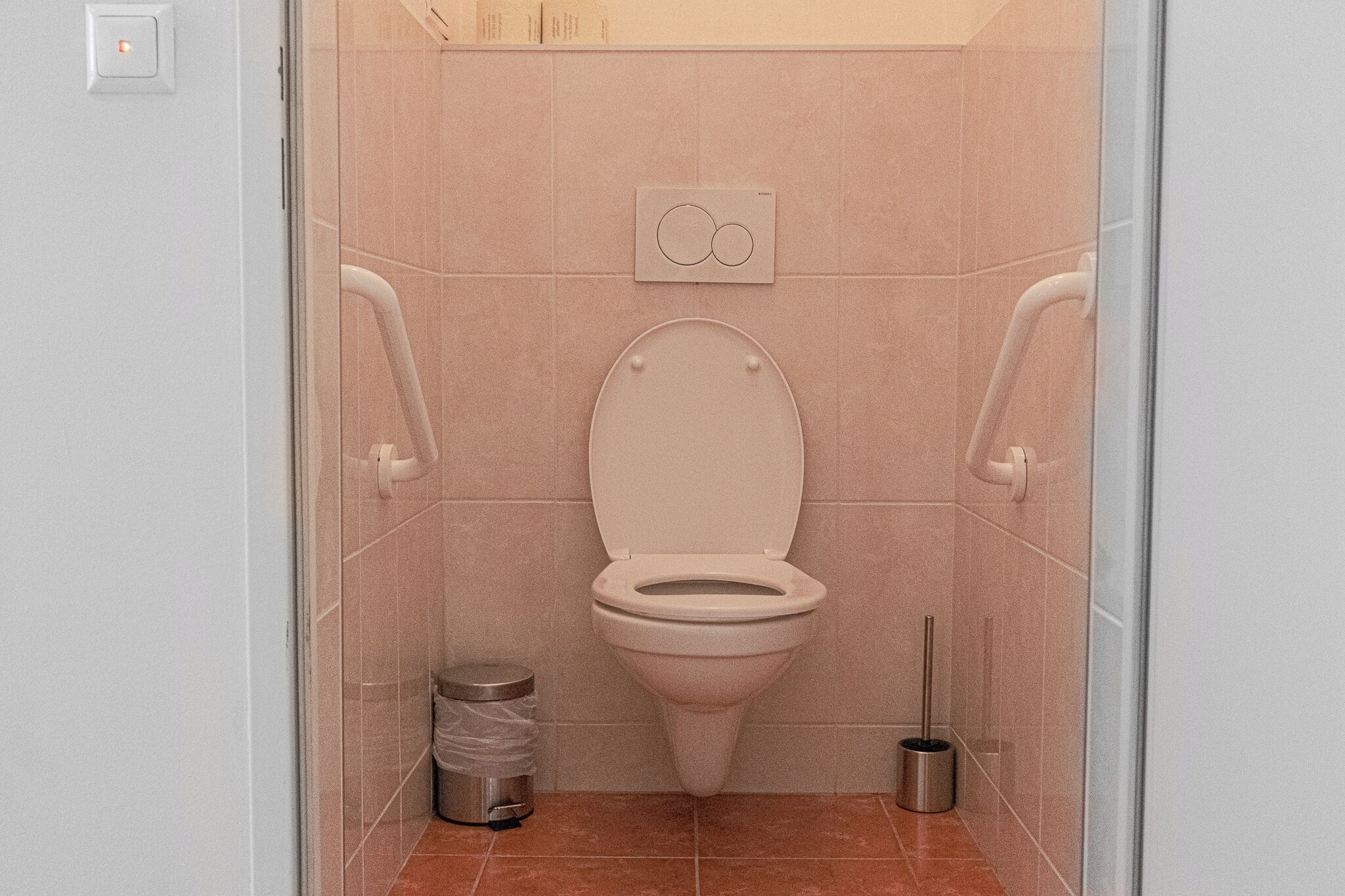 A modern bathroom with a toilet, a trash bin, and a bidet.