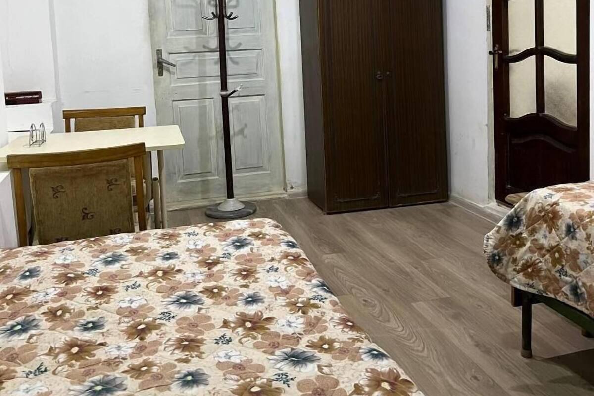Una camera da letto con un letto, un armadio in legno, un appendiabiti e una scrivania con sedie.