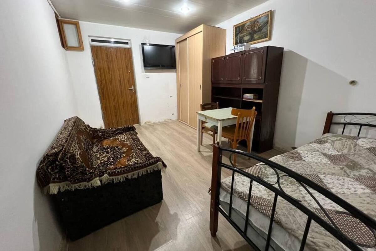 Una camera da letto con un letto, una scrivania, una sedia, un armadio e una televisione.