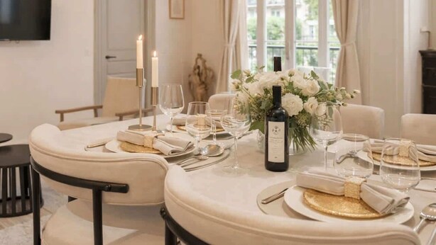 Comedor con una mesa redonda para cuatro personas, velas y un florero con flores.