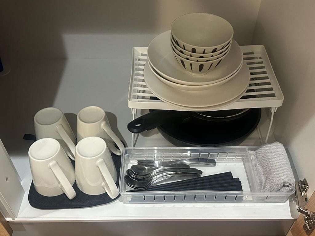 A kitchen area with white storage shelves holding plates, bowls, and mugs.