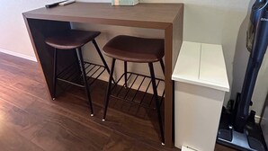 Un espace de travail compact doté d’un bureau en bois et de deux tabourets.