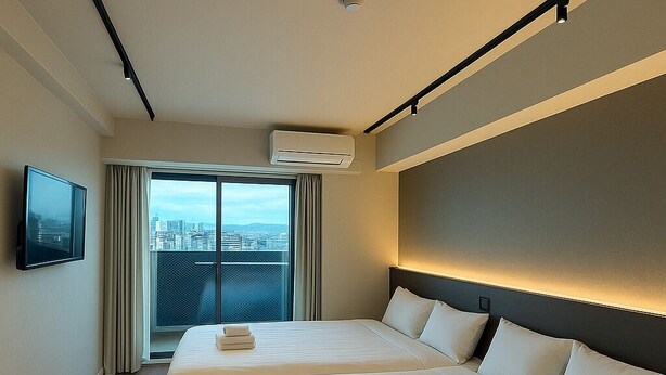 Une chambre d’hôtel avec deux lits, un téléviseur à écran plat, la climatisation et une vue sur la ville.
