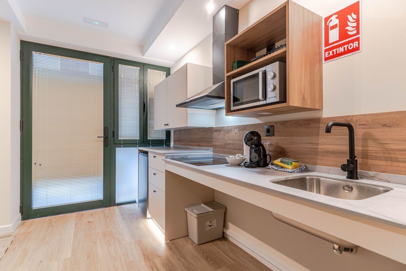 A modern kitchen with a built-in microwave, a coffee maker, and a sink.