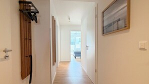 Un pasillo con suelo de madera, un radiador, un perchero y un cuadro en la pared.