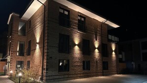 Un edificio de ladrillo de varios pisos con ventanas iluminadas y techo plano.