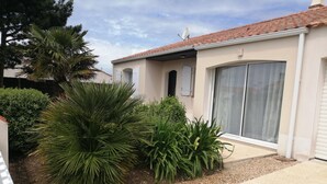 Un edificio residencial con techo de tejas, puerta corrediza de vidrio y entrada con grava.