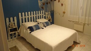 Un dormitorio con cama, cabecero de madera, un adorno en la pared y una ventana con cortinas.