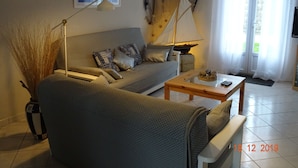 Una sala de estar con un sofá, una mesa de centro, una lámpara y una reproducción decorativa de un velero.