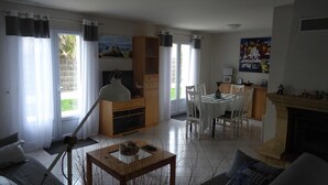Una sala de estar con un sofá, una mesa de centro, un televisor, una chimenea y un comedor con sillas y una mesa.