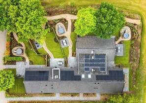 An aerial view of a building with a flat roof, solar panels, and a garden area with trees and pathways. - Comfortable ground-floor accommodation for 2 persons with a private hot tub in the garden. Compact in size, yet warmly and fully furnished. (Otterlo)