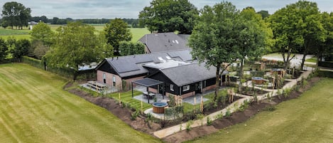 A modern house with a large garden, solar panels, and a swimming pool.