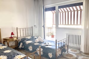 A bedroom with a bed, a nightstand, a red lamp, and a view of the outside balcony. - Appartamento Mare Blu - Terracina (Terracina)