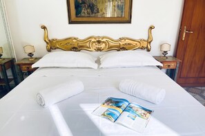 A neatly made bed with white linens, two pillows, and two rolled towels. A magazine is placed on the bed. - Appartamento Mare Blu - Terracina (Terracina)