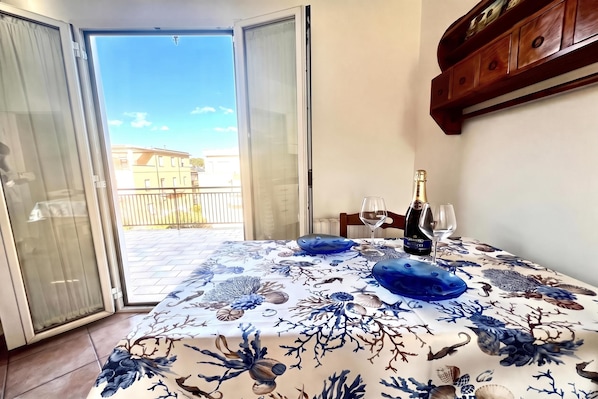A dining area with a table set for two, a bottle of wine, and two glasses. - Appartamento Mare Blu - Terracina (Terracina)